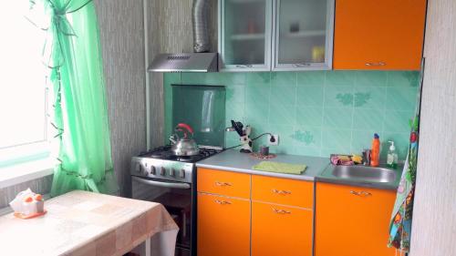 ウシンスクにあるАпартаменты на Возейской, 3 (7эт)のキッチン(オレンジ色のキャビネット、コンロ、シンク付)