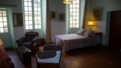 une chambre avec un lit, une chaise et des fenêtres dans l'établissement La Salamandre, à Sarlat-la-Canéda