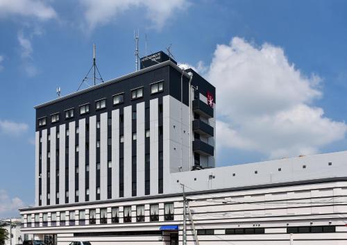 a large white building with a flag on top of it at Hotel Sunroute Tochigi in Tochigi