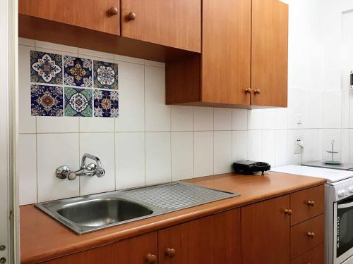 La cuisine est équipée d'un évier et de placards en bois. dans l'établissement Comfortable Engomi Apartment, à Yukarı Lakatamya