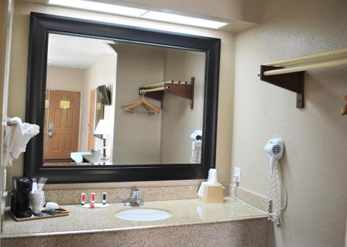 a bathroom with a sink and a large mirror at Super 8 by Wyndham Galveston in Galveston