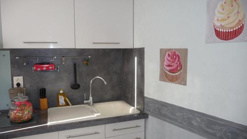 - une cuisine avec un évier et un petit gâteau au mur dans l'établissement La Bonbonnière, à Sarlat-la-Canéda