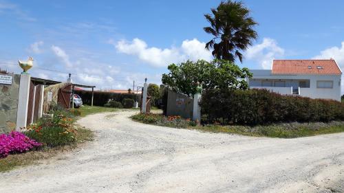 a dirt road in front of a house with flowers at Apartamentos na Quinta Altavista do Carvalhal in Zambujeira do Mar