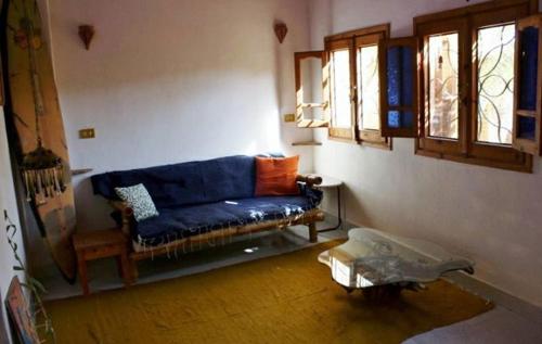 a living room with a blue couch and windows at Jillyfish House Dahab - deine Oase in zwei Palmengärten - zentral am 'Lighthouse' in Dahab