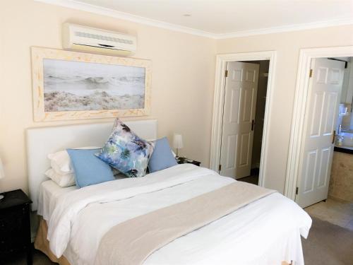 a bedroom with a white bed with blue pillows at Hout Bay Breeze Guest House in Hout Bay