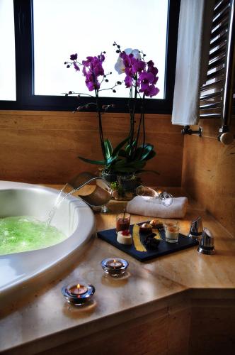 a bathroom with a bath tub and a vase of flowers at Pazo Los Escudos Hotel Spa & Resort in Vigo