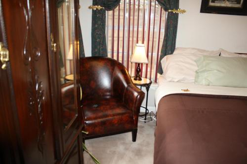 a bedroom with a bed and a brown leather chair at Woodrow House Bed & Breakfast in Lubbock