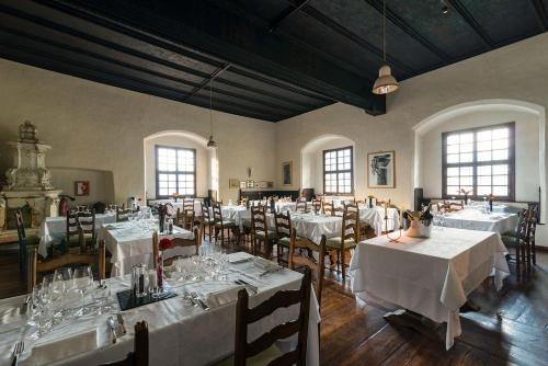 ein Esszimmer mit weißen Tischen, Stühlen und Fenstern in der Unterkunft Castel Pergine in Pergine Valsugana
