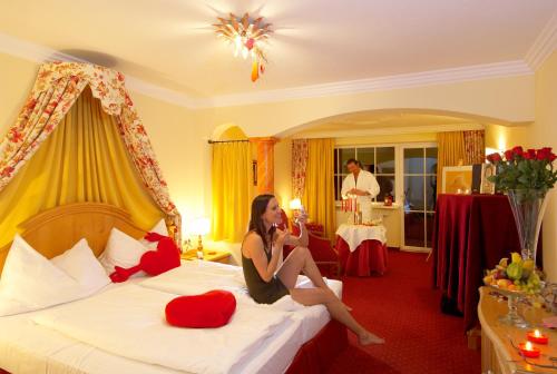 a woman sitting on a bed in a hotel room at Wohlfühlresort und Feriengut Martinerhof in Sankt Martin am Tennengebirge