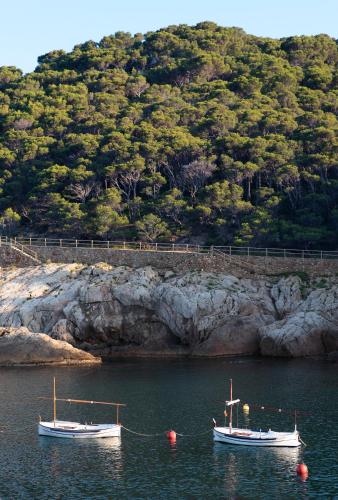 two boats are docked in the water near a mountain at Hostal Sa Rascassa in Begur