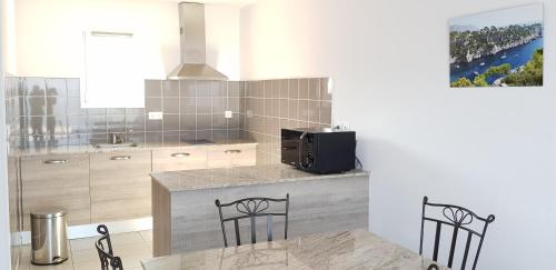 une cuisine avec un comptoir avec deux chaises et un four micro-ondes dans l'établissement Residence de Tourisme la Provence, à Istres