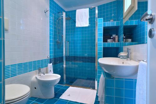 Un baño con azulejos azules, inodoro y lavabo. en Mareluna, en Nerano