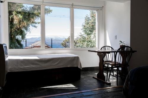 1 dormitorio con cama, mesa y ventanas en La Fontana Cabañas en San Carlos de Bariloche