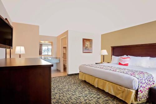 a hotel room with a bed and a flat screen tv at Days Inn by Wyndham Lakewood South Tacoma in Lakewood