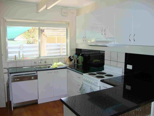 cocina con electrodomésticos blancos y ventana grande en Ageri Holiday House, en Bright