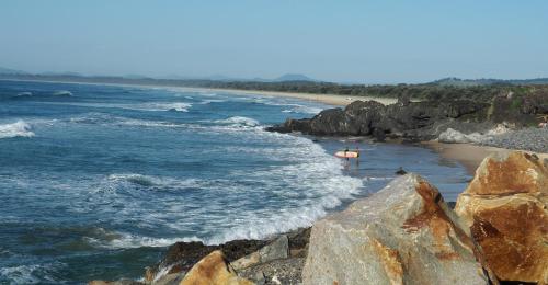 a beach with some rocks and the ocean at Jetty House in Coffs Harbour