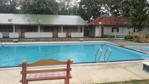a swimming pool with a bench in front of a house at Friends Paradise in Kilinochchi