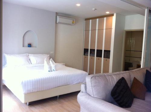 a bedroom with a white bed and a couch at BanSanKram by Patsara in Cha Am