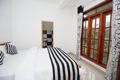1 dormitorio con cama y ventana en Isuru Homestay, en Ella