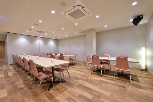 a conference room with tables and chairs and a projector at Hotel Hanakomichi in Nara