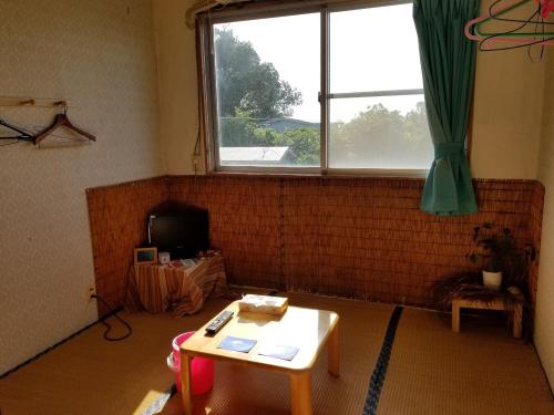 a living room with a table and a window at Minshuku Myojoso in Yoron