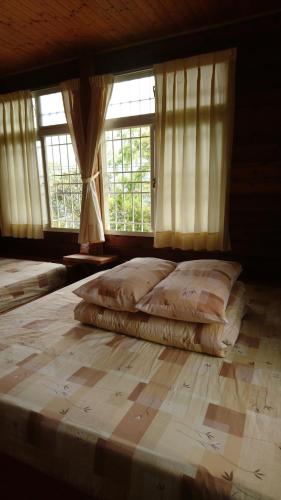 a bedroom with two beds and two windows at An Yun Mountain Homestay in Meishan