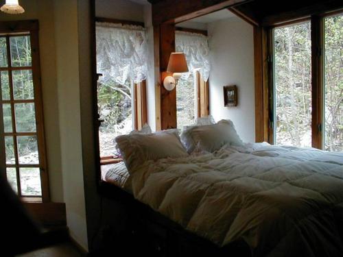 Schlafzimmer mit einem großen Bett vor den Fenstern in der Unterkunft Mountain Valley Retreat in Killington