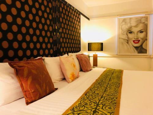 a bed with pillows and a painting of a woman at Baipho Lifestyle in Patong Beach