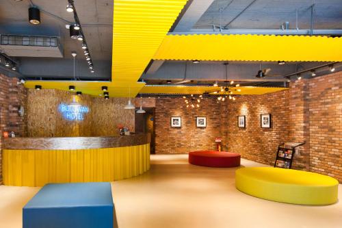 un hall avec des tables jaunes et bleues et un mur en briques dans l'établissement Bulowan Hotel, à Hualien