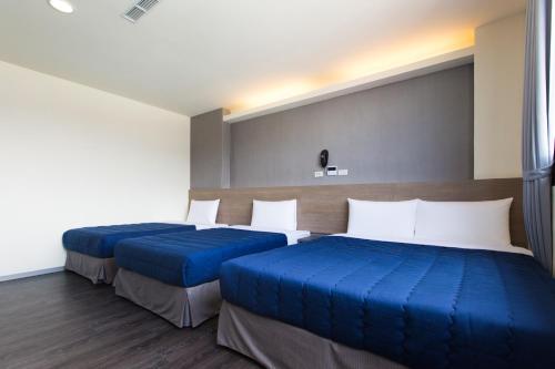 two beds in a hotel room with blue sheets at Bulowan Hotel in Hualien City