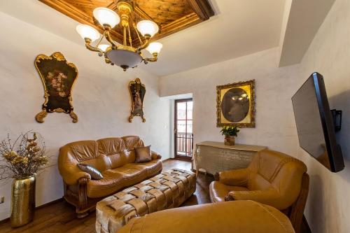 a living room with leather furniture and a chandelier at Arcadie Hotel & Apartments in Český Krumlov