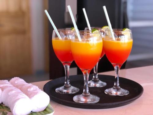 four glasses of orange juice on a black tray at Evila Inn - Thoddoo in Thoddoo