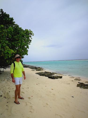 a man standing on a beach next to the ocean at Evila Inn - Thoddoo in Thoddoo
