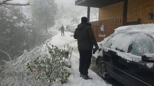 a man standing next to a snow covered car at The fairy land - Lala Mountain in Fuxing
