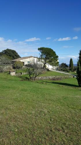 un champ d'herbe avec un bâtiment en arrière-plan dans l'établissement Gîte - Mas de Louise, à Rousson