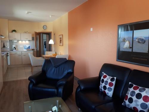 a living room with two chairs and a flat screen tv at Ferienwohnungen Auf der Düne in Cuxhaven