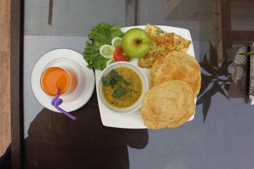 a plate of food with an apple and a bowl of soup at Anchorage The Residence in Dhaka