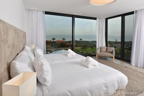 two beds in a bedroom with a large window at Villa J in Migdal