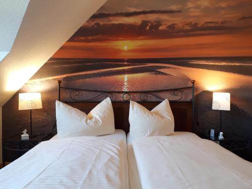 two beds in a room with a painting on the wall at Ferienwohnungen Auf der Düne in Cuxhaven