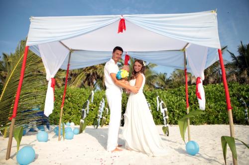 a bride and groom standing under a tent on the beach at Evila Inn - Thoddoo in Thoddoo