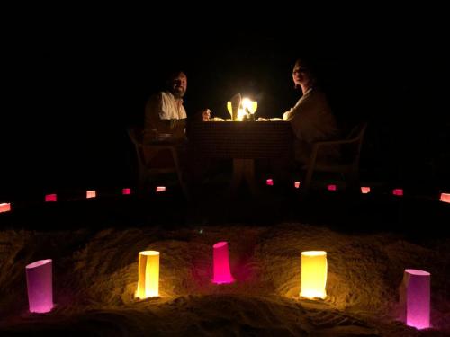 two men sitting at a table in the sand with candles at Evila Inn - Thoddoo in Thoddoo