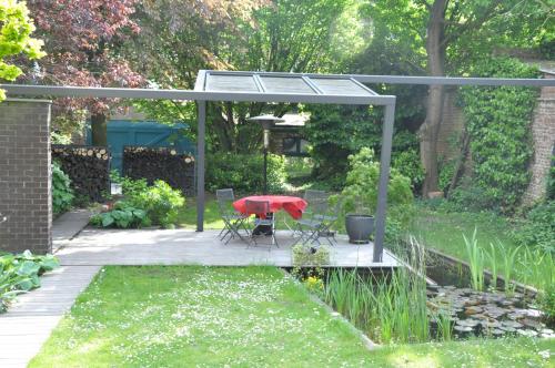 a patio with a red table and chairs in a garden at B&B Compagnons11 in Mons