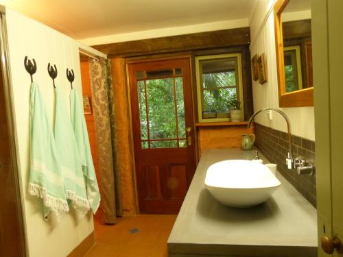 a bathroom with a white sink and a door at The Stables in Cooroy