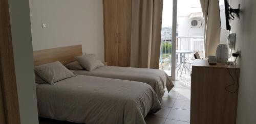 a hotel room with two beds and a balcony at Sunny Napa Apartments in Ayia Napa