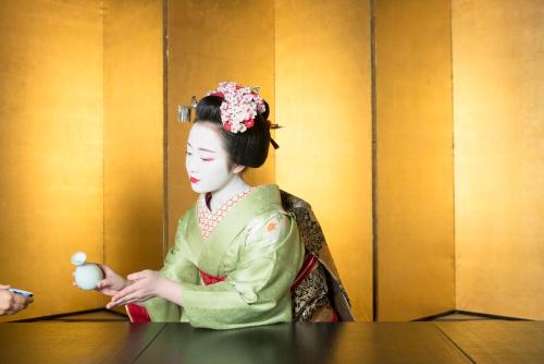 a woman in geisha attire sitting at a table at Kamishichiken Oku in Kyoto