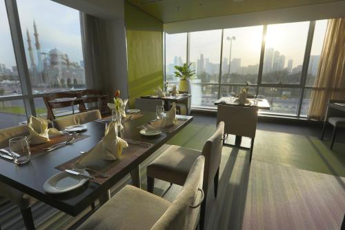 a dining room with tables and chairs and a large window at 72 Hotel Sharjah in Sharjah