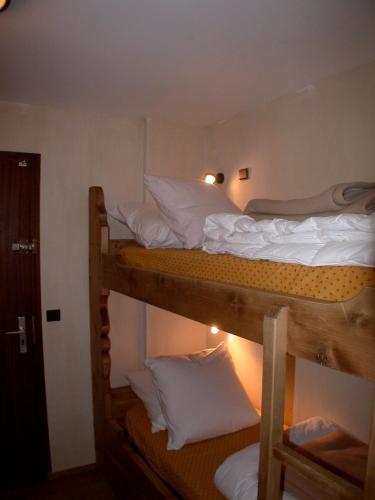 Cette chambre comprend 3 lits superposés avec des draps blancs. dans l'établissement Le Carlton, à Chamonix-Mont-Blanc