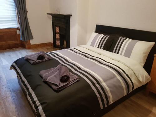 a bedroom with a bed with two towels on it at Rozina Apartment in Paisley