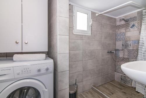 a bathroom with a washing machine and a sink at Semeli Apartment in Zakynthos