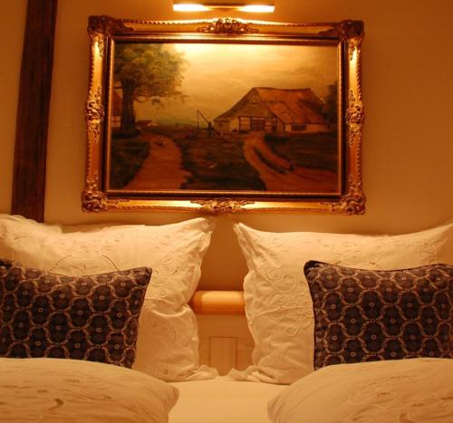 a picture of a painting above a bed with pillows at Hotel & Café Mohrenbrunnen in Eisenberg